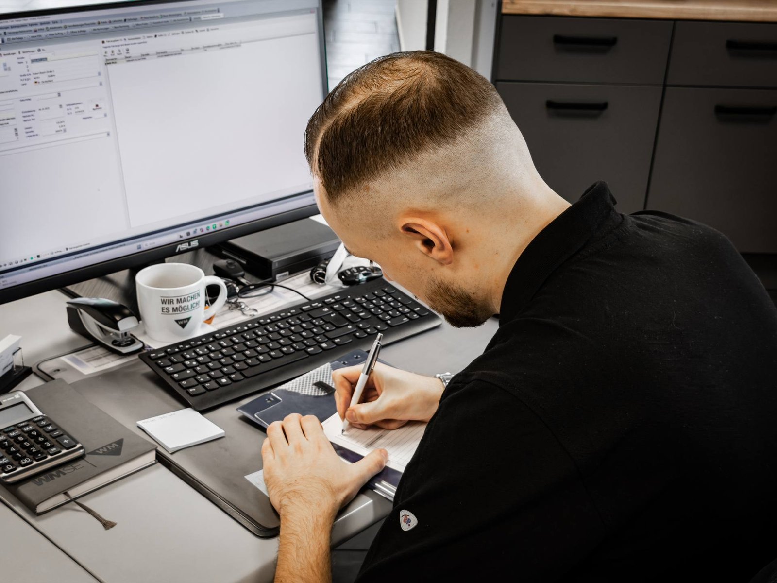 Mitarbeiter dokumentiert einen Werkstattauftrag am Schreibtisch